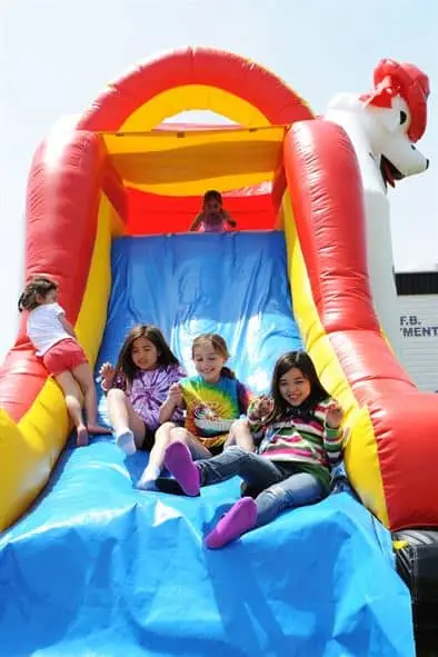 Kids enjoying colorful inflatable bounce house slide rental West Michigan
